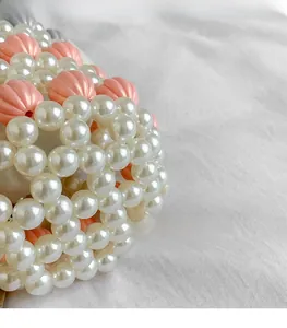 Détail d'un sac perlé fait main avec perles citrouille roses et perles blanches