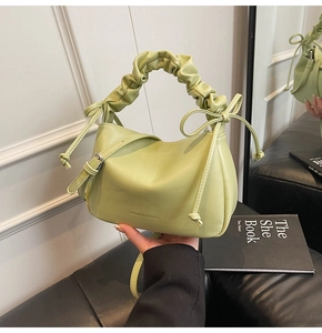 Close-up of light green cloud bag featuring bow drawstrings and ruched handle detail