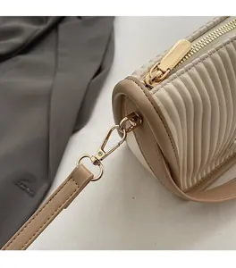 Detailed close-up of light gold hardware and cream pleated faux leather on a bucket bag