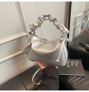 Detail of silver metallic shoulder bag featuring a ruched handle and fashion logo