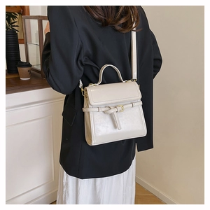 Detail of cream vintage faux leather handbag with gold buckle and top handle