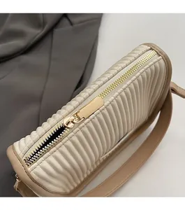 Close-up of smooth gold zipper and pleated texture on cream bucket bag detail
