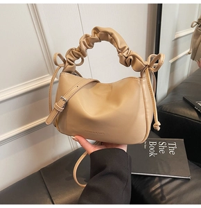 Close-up of soft khaki PU leather handbag featuring elegant pleats and side bow drawstring