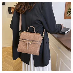 Detail showing vintage brown crossbody bag with leather texture and golden buckle details
