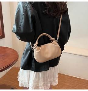 Detail of beige faux leather handbag showing soft pleated texture and shoulder strap