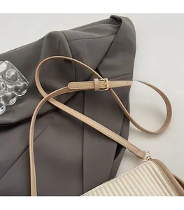 Detail of adjustable beige leather shoulder strap with gold buckle on a pleated bucket bag