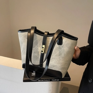 Grand sac cabas gris avec garniture noire et fermoir doré, idéal pour les trajets quotidiens