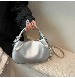 Detailed view of silver metallic bag with knotted handle and pleated texture design