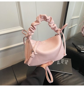 Detail of pink soft leather shoulder bag with ruffled handle and side bow accents