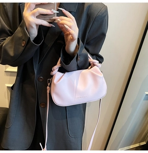 Detail of light pink pleated cloud bag with knotted handle and fashion logo lettering