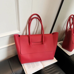 Red lychee pattern leather tote bag with double handles in a modern interior setting