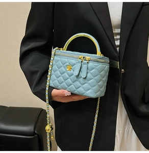 Detail of light blue quilted vanity bag with golden floral clasp and metal handle
