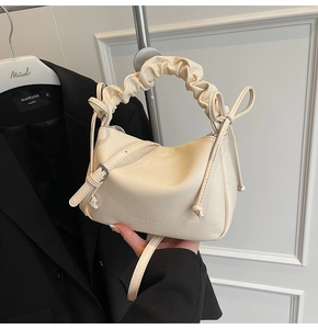 Detailed shot of cream soft leather handbag with pleated handle and side bow knot detail