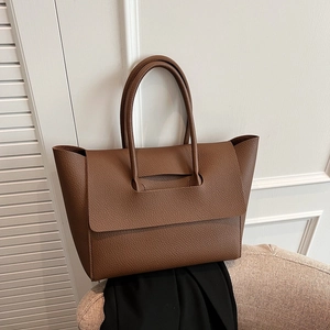 Brown lychee leather tote bag with large flap and top handles in a lifestyle setting