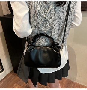 Detail view of the black cloud-shaped pleated bag with Fashion & Bags logo on the side