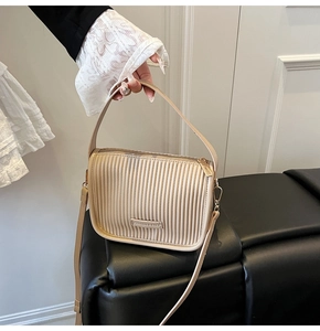 Detail of beige pleated bucket bag featuring vertical stripes and gold metal hardware