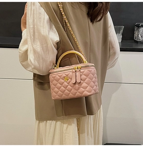 Detailed close-up of pink quilted crossbody bag with gold camellia logo and chain strap