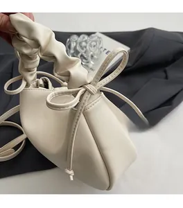 Detail of cream soft leather handbag featuring a ruched handle and bow decoration