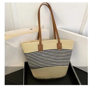 Detail of hand-woven straw tote with blue and white stripes and brown PU leather handles