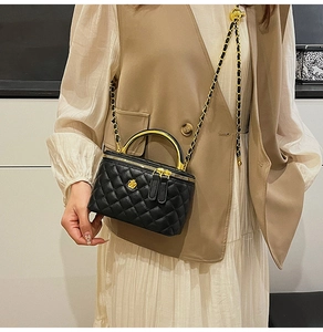Close-up of quilted black crossbody bag with gold floral hardware and chain strap