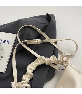Detail of cream pleated cloud handle bag with silver hardware on grey suit fabric