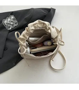 Interior view of beige pleated handbag showing spacious capacity for cosmetics and phone