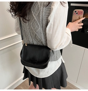 Detail of black pleated shoulder bag with fashion and bags metal plaque and gold hardware
