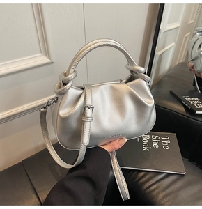 Detail of silver metallic dumpling bag with knotted handle and fashion text on leather
