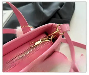 Close-up of pink bucket bag showing smooth zipper closure and fuzzy ball keychain detail