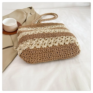 Détail d'un cabas en paille tressée avec crochet floral ajouré et rayures bicolores