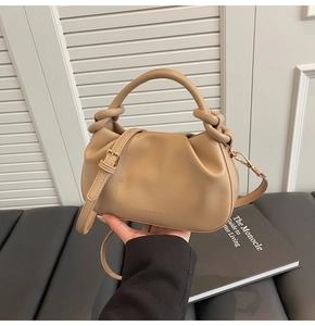 Detail of beige knotted handle handbag with Fashion & Bags logo and gold hardware