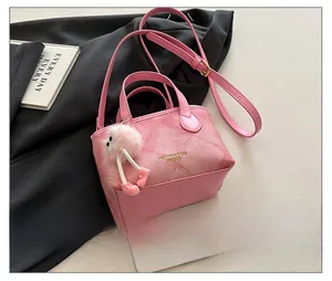 Detail view of pink bucket bag with woven texture, plush charm, and smartphone for scale