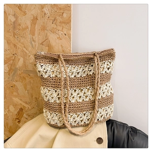 Détail du motif floral évidé tissé sur un sac fourre-tout en paille fait main avec anses