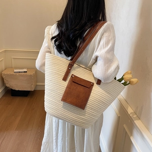 Large cream straw tote bag with brown leather straps shown on a model's shoulder