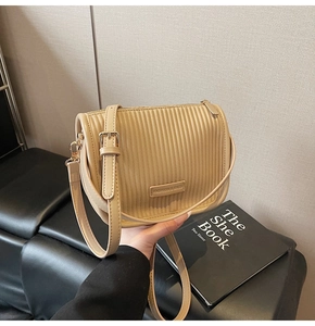 Detail of pleated khaki bucket bag with gold-tone hardware and adjustable shoulder strap