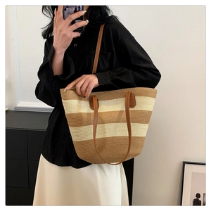 Detail of striped woven tote bag with brown leather handles and reinforced stitching