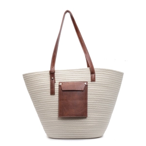 Straw tote bag with brown leather handles and front pocket on white background