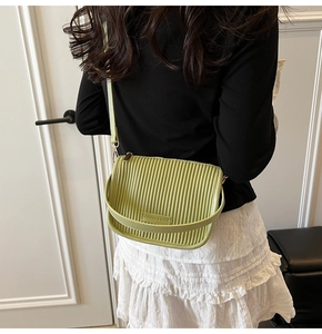 Detail of light green pleated bucket bag showing embossed fashion logo and metal hardware