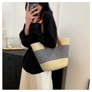 Detail of summer straw tote bag with navy stripes and brown faux leather handles