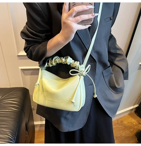 Detail of mint green shoulder bag featuring ruched handle and bow knot decoration