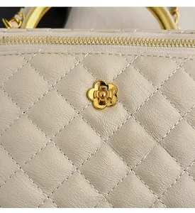 Detail of beige quilted leather handbag showing stitching and golden flower emblem