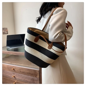 Detail view of striped straw tote bag with brown leather handles for summer travel