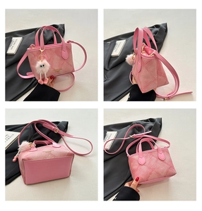 Detail view of pink patchwork bucket bag with crossbody strap and pompom charm