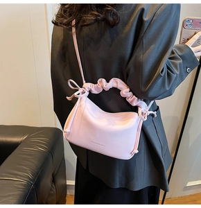 Detailed side view of light pink soft leather half-moon shoulder bag with ruched strap