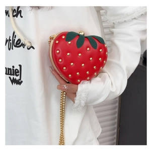 Detail of strawberry shaped crossbody bag with gold studs and green leaf closure clasp