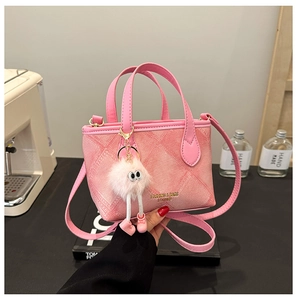 Pink bucket bag with leather handles, gold logo lettering and a plush doll pendant detail