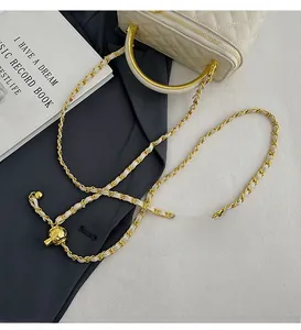 Close-up of beige quilted crossbody bag with gold chain strap and metal ball detail