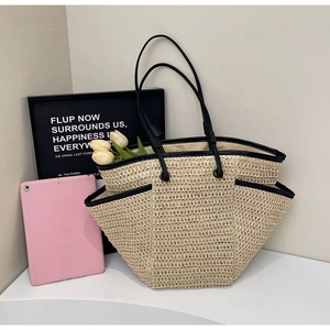 Détail d'un sac cabas en paille avec poignée en cuir noir et design de poche latérale