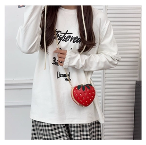 Close-up of strawberry shaped crossbody bag with red shell and gold stud details
