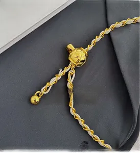 Close-up of golden diamond-quilted metal ball buckle on woven leather chain strap